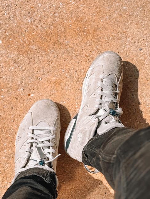 Person wearing grey lifestyle sneakers on a concrete ground