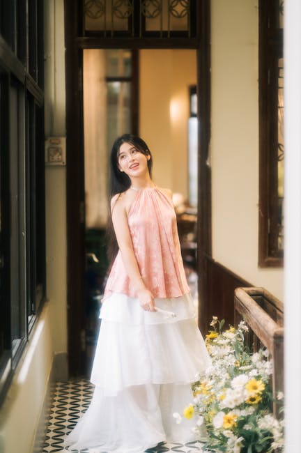 Elegant woman in pink and white fashion standing in a bright hallway